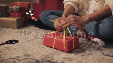 紧紧抓住女孩的手，最后包装圣诞礼物。 女孩在家里地板上绑着<strong>黄色丝带</strong>